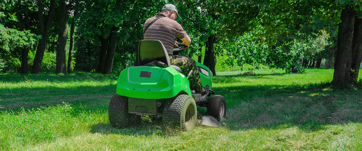 Mitarbeiter mäht große Grünflächen mit einem Aufsitzmäher für ein gleichmäßiges und gepflegtes Rasenergebnis.