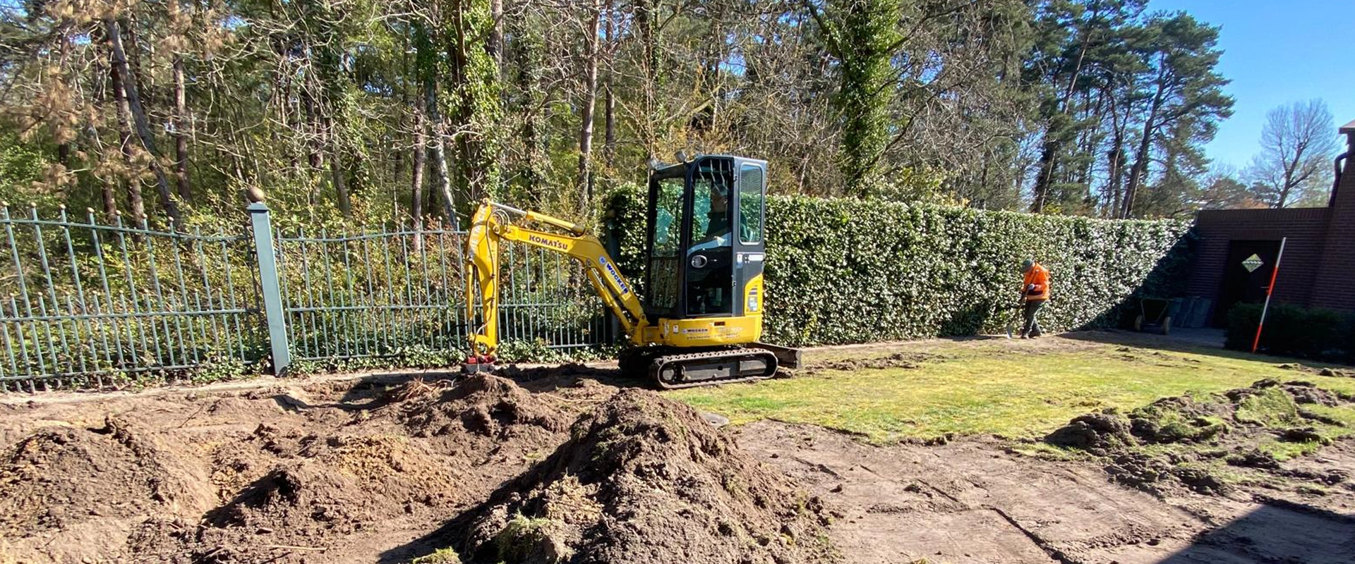 Kleiner Bagger führt präzise Erdarbeiten im Garten durch und bereitet Flächen für Gestaltung oder Bauarbeiten vor.